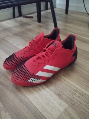 Adidas fotbollsskor - Adidas demon skin nypris 1200 .Säljer ett par röda Adidas fotbollsskor med svarta och vita detaljer. Skorna har klassiska tre vita ränder på sidan och svart mönster på tån. Yttermaterialet är syntet och designen är slimmad för bra bollkontroll. Perfekta för dig som vill sticka ut på planen