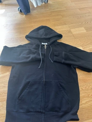 Zip hoodie - Säljer en svart hoodie från Carhartt i storlek XS. Hoodien har dragkedja framtill, två stora fickor och justerbar huva med snören. Tillverkad i mjukt bomullsmaterial, perfekt för en avslappnad streetwear-look.