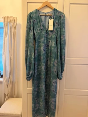 Positano maxi klänning från Adoore - Långklänning i ljusblått med blommigt mönster från Adoore. Aldrig använd.