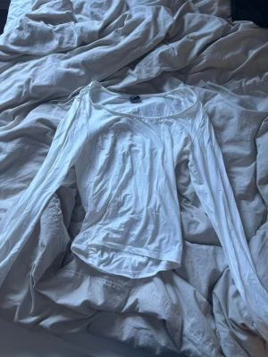Vit långärmad topp Gina Tricot - Säljer en enkel och stilren vit långärmad topp från Gina Tricot som aldrig är använd. Toppen har en rundad halsringning och är gjord i mjuk bomull, perfekt att matcha med jeans eller kjol. Passar dig som gillar basic-plagg med clean look. 