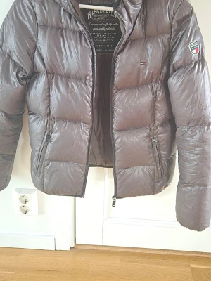 Tommy Hilfiger dunjacka grön - Supersnygg dunjacka från Hilfiger Denim / Tommy Hilfiger. Färgen är mörkgrön / buteljgrön. Tyvärr jättesvår färg att fota. Ren och fräsch men har normalt bruksslitage, som lite noppor vid ärmslut, och lite nött längs dragkedjor och fickor plus en lagning bak på höger ärm ca 2.5 cm. Se bilder! Är en M men pytteliten i storlek och passar stl XS el 32/34!