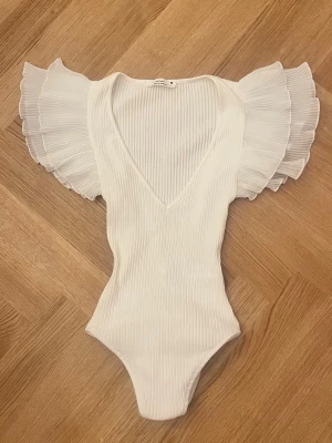Vit body med volangärmar💗 - Supersnygg vit body med djup V-ringning och breda volangärmar i plisserat tyg. Perfekt att styla till en jeanskjol till exempel och allmänt inför sommarn!!🌺💗Se mini lagning på nästsista bilden