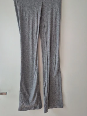 Grå ribbade leggings från Gina Tricot - Snygga grå leggings från Gina Tricot i ribbat stretchigt material. Modellen har utsvängda ben och en bekväm midja. Perfekta för en avslappnad och trendig look. Yoga pants. Storlek 158/164