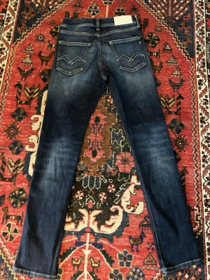 Mörkblå Replay jeans med kontrastsömmar hyperflex - Snygga mörkblå jeans från Replay med raka ben och kontrastsömmar. Bakfickorna har coola broderade detaljer och klassisk Replay-lapp i midjan. Perfekta för dig som gillar en tidlös och avslappnad stil.