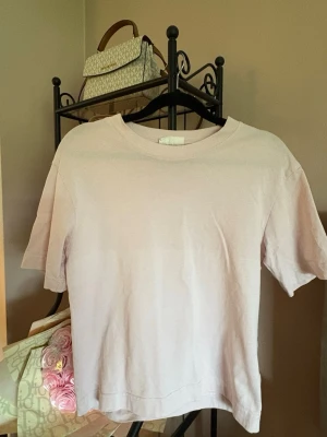 Ljusrosa basic t-shirt Gina Tricot - En ljusrosa basic t-shirt från Gina Tricot, basically basics-kollektionen. T-shirten har rund halsringning och korta ärmar. Tillverkad i mjuk bomull som känns skön mot huden. Perfekt till alla dina outfits.