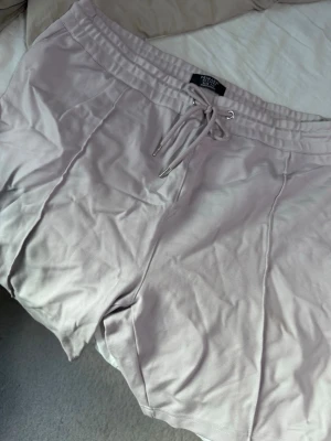 Ljuslila shorts från Primark - Säljer ett par ljuslila shorts från Primark i storlek 2XL. De har slim fit-passform, resår i midjan och snörning framtill för justerbar komfort. Perfekta för varma dagar och chill stunder.