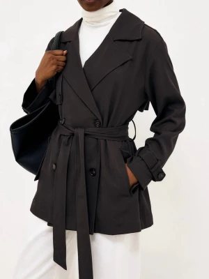 Kort trenchcoat nakd - Stilren brun trenchcoat i kortare modell från NAKD med dubbelknäppning, breda slag och knytskärp i midjan. Jackan har sidofickor och justerbara remmar vid ärmsluten. Nypris 1000