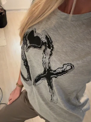 The weeknd T-shirt - Säljer en grå the weeknd t-shirt med ett stort svart grafiskt tryck på framsidan. T-shirten har rund halsringning och korta ärmar. Obs, inte köpt på konserten men liknar väldigt mycket de som såldes under Europaturnén. Helt i nyskick och aldrig använd 🩷