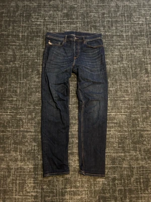 Mörkblå raka jeans herr - Säljer ett par mörkblå jeans med raka ben och klassisk femficksdesign. Jeansen har kontrastsömmar och patch bak i midjan. Materialet är denim i bomull och passformen är smal men inte supertight. Storlek W30 och L32.