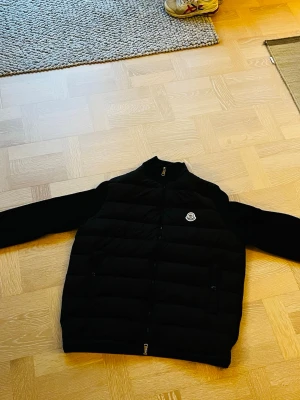 Svart cardigan från Moncler - Snygg svart dunjacka från Moncler med quiltad design. Jackan har två dragkedjeförsedda fickor framtill. Finns inga defekter på jackan, använd endast några gånger, NFC kod finns se bild 3. Hör av dig vid funderingar!