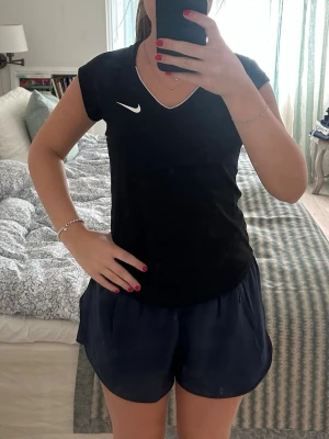 Svart sport/tennis- topp från Nike - Snygg svart sport-topp från Nike med vit logga på bröstet och V-ringning. 