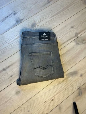 Gråa Replay jeans med raka ben - Snygga gråa jeans från Replay med raka ben och klassisk femficksmodell. Jeansen har diskreta slitningar framtill och en broderad bakficka. Tillverkade i mjuk denim som ger en avslappnad look.