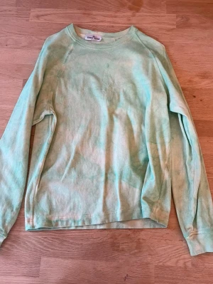 Mintgrön stone island hoodie - En mintgrön långärmad sweatshirt i mjuk bomull. Tröjan har en avslappnad passform och rund halsringning. Perfekt för chill dagar eller när du vill ha en enkel och stilren look.