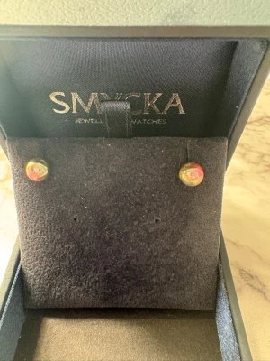 Färgglada pärlörhängen från Smycka - Säljer ett par små pärlörhängen från Smycka i flera färger, bland annat rött och gult. Örhängena har en rund form och sitter i en elegant ask. Perfekta för dig som vill ha något unikt och färgstarkt till din stil.