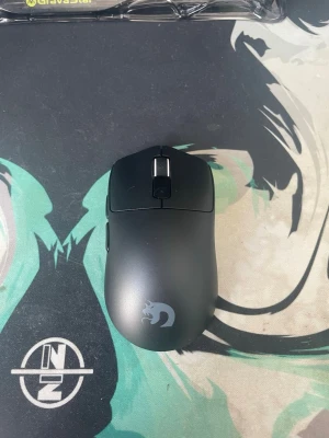 Svart trådlös gamingmus - Snygg svart trådlös gamingmus med ergonomisk form och diskret logga på ovansidan. Musen har två huvudknappar, scrollhjul i silver och sidoknappar för extra funktionalitet. Passar perfekt för gaming eller arbete vid datorn.