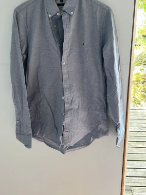 Grå slim fit skjorta Tommy Hilfiger - Snygg grå skjorta från Tommy Hilfiger i slim fit stretch-modell. Skjortan har klassisk krage med knappar, långa ärmar och små vita knappar framtill. Liten logga på bröstet för en clean look.