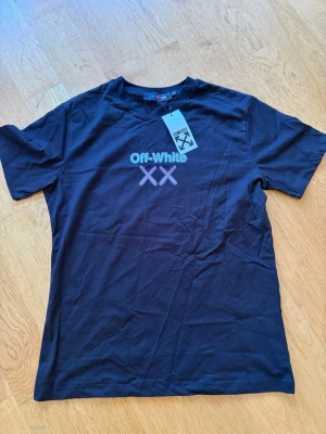 Svart Off-White t-shirt med tryck - Snygg svart t-shirt från Off-White med trycket 'Off-White XX' i vitt och rosa på bröstet. Klassisk rund hals och korta ärmar. Perfekt för dig som gillar streetwear och vill ha en stilren men ändå unik look.
