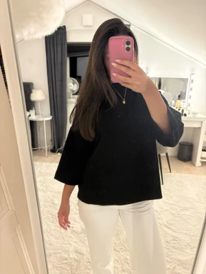 Svart tjocktröja med trekvartsärm - Säljer en svart topp med lös passform och trekvartsärmar. Toppen har en enkel, stilren design och är perfekt att matcha med olika outfits. Materialet känns mjukt och bekvämt mot huden. Passar dig som gillar en avslappnad men snygg look.