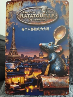 Ratatouille metallskylt Paris - Cool metallskylt med motiv från Disney Pixar-filmen Ratatouille. Skylten visar Remy med en träslev framför Eiffeltornet och Paris i bakgrunden. Text på både engelska och kinesiska. Perfekt som dekoration för kök eller filmrum.