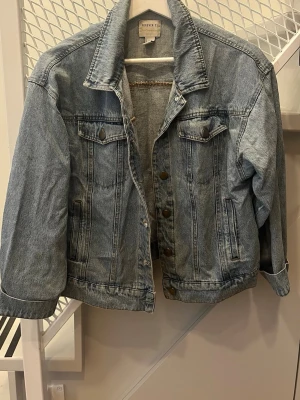 Ljusblå klassisk jeansjacka - Snygg ljusblå jeansjacka från Forever 21 med raka ärmar, klassisk krage och bröstfickor med lock. Jackan har knappar framtill och är gjord i slitstarkt denimtyg. Perfekt för en avslappnad och trendig look.