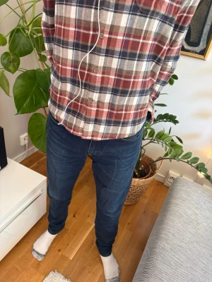 Mörkblå j.Lindeberg jeans - Säljer ett par mörkblå slim fit jeans med klassisk femficksdesign och metallknappar. Jeansen har en diskret logga i metall på myntfickan och är tillverkade i ett mjukt denimtyg med lite stretch för extra komfort.