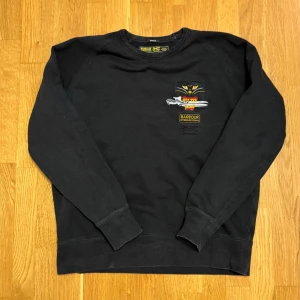 Barbour Sweatshirt - Barbour International x Denham – 10 Years Anniversary Edition  Sällsynt och exklusiv collab-sweatshirt i svart. Relaxed fit, storlek M. Broderad Barbour International x Denham-grafik framtill. Inga hål eller skador, men har tappat lite färg på grund av användning, se bilder. Klassisk och svårhittad jubileumsmodell.