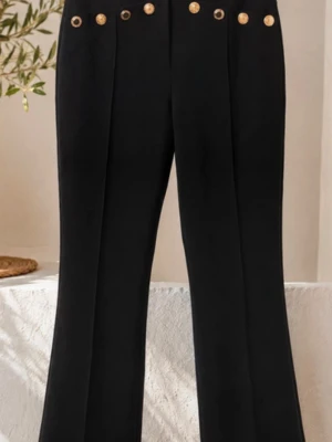 Svarta kostymbyxor med guldknappar - Stilrena svarta kostymbyxor med raka ben och dekorativa guldknappar i midjan. Byxorna har pressveck framtill och en klassisk, elegant look. Perfekta för dig som vill ha en dressad vibe med en twist.