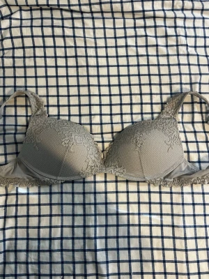 Intimissimi Grå spets-bh med vadderade kupor - Snygg grå bh med vadderade kupor och fina spetsdetaljer över hela framsidan och axelbanden. Bh:n har en mjuk struktur och spetskant nedtill som ger en romantisk känsla. Perfekt för dig som gillar en feminin och bekväm stil. Nyskick!🍂💕