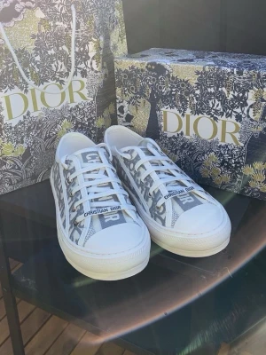  gråvita låga sneakers - Snygga låga sneakers i vitt och grått med det klassiska monogrammönstret. Skorna har vita snören, vit sula. Perfekta för dig som vill ha en exklusiv och trendig look. Pris går att diskuteras vid snabb affär. Hör av dig gärna!