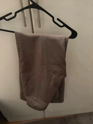 Beige kostymbyxor  med rak passform - Snygga beige kostym byxor med rak passform och klassisk design. Perfekta för en avslappnad och stilren look. Byxorna har en mjuk känsla och är tillverkade i ett lätt linnematerial som andas.