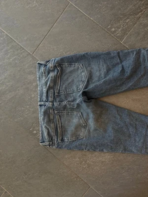Gina Young 14+ Blå bootcut jeans - Säljer ett par blå bootcut lågmidjade jeans med slitningar på låret och knäna. Jeansen har två framfickor och två bakfickor samt en låg midja. Materialet är klassisk denim i bomull och passformen är utsvängd nedtill. Storlek M (Young storlekar så mer som en vanlig S) Använda ett par gånger passar inte längre och säljs därför🩵