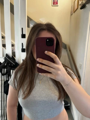 Grå croppad ribbad topp  - Säljer en ljusgrå croppad topp från Fashionsta. Toppen är ribbad, har rund halsringning och korta ärmar. Perfekt till jeans eller kjol för en enkel och snygg look.