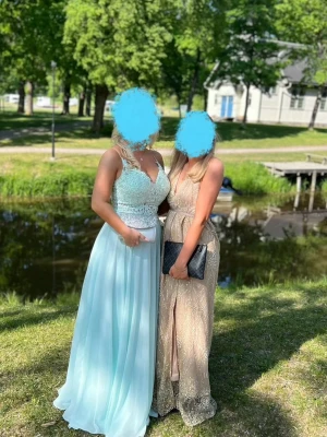 Ljusblå balklänning  - ljusblå långklänning med v-ringad spets upptill och tunna axelband. Kjolen är i ett lätt, svepande material som ger en drömmig känsla. Perfekt för bal eller student. Klänningen har markerad midja och vackra detaljer. Prutbar vid snabb affär