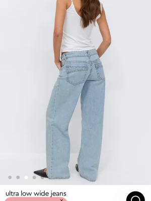 Ultra low wide jeans i ljusblå denim - Säljer ett par ultra low wide jeans i ljusblå denim med riktigt breda ben och låg midja. Jeansen har klassiska fem fickor och synliga sömmar. Perfekta för en avslappnad och trendig look.