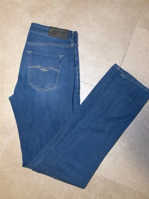 Blå jeans från Replay - Snygga blå jeans från Replay med klassisk femficksdesign och raka ben. Jeansen har en diskret logga på bakfickan och är tillverkade i mjukt denimtyg som ger en bekväm passform. Perfekta för en avslappnad och trendig stil. Inga defekter. Super skick! Hör av dig vid frågor!