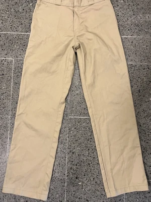 Dickies byxor W30/L32 – Som nya! - Snygga Dickies-byxor i trendig brun/ljusbeige färg, använd endast en gång – i princip nyskick! Säljes endast på grund av fel storlek.  Klassisk Dickies-passform med slitstarkt material och tidlös stil – perfekt till både vardag och jobb. Passar dig som gillar streetwear med kvalitet och hållbarhet.  Storlek: W30 / L32 Färg: Brun / ljusbeige Skick: Använd en gång – som nya!