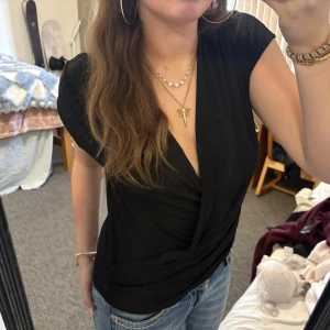 Svart omlott topp med v-ringning - Snygg svart omlott topp med v-ringning och korta ärmar. Perfekt att klä ner för vardags eller klä upp för fest💕
