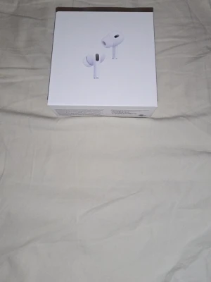 Apple AirPods Pro trådlösa hörlurar - Säljer ett par Apple AirPods Pro med vit laddningsetui. Hörlurarna är trådlösa in-ear-modell och levereras i originalförpackning. Snygg och stilren design i vitt plastmaterial, perfekt för dig som vill ha grymt ljud och smidig anslutning till din iPhone.