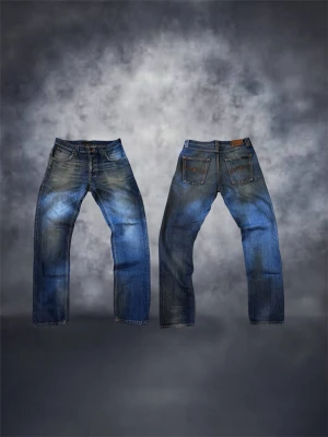 Nudie jeans steady eddie - Säljer ett par klassiska blå jeans från Nudie Jeans Co med raka ben och snygg slitning. Jeansen har fem fickor, orangea sömmar och är gjorda i denim. Perfekta för dig som gillar en avslappnad och tidlös stil.