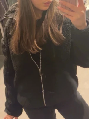 Svart teddyjacka med dragkedja - Mysig svart teddyjacka med mjuk, fluffig yta och hel dragkedja framtill. Storlek S-M
