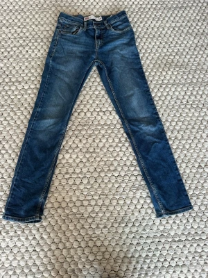 Levi's 512 Slim Taper jeans blå - Säljer ett par blå Levi's 512 Slim Taper jeans med klassisk femficksdesign och smal passform. Jeansen har snygga slitningar och gul kontrastsöm. Perfekta för dig som gillar en modern och smal siluett. Materialet är klassisk denim i bomull.