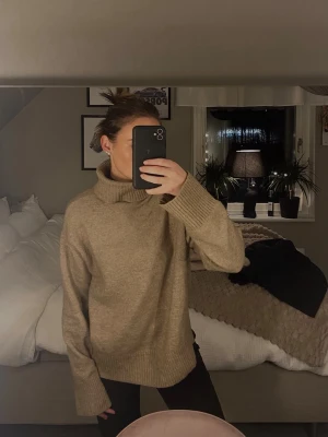Beige/brun  polotröja  - Säljer en beige/brun stickad polotröja från H&M med oversized passform och långa ärmar. Tröjan har ribbstickad krage och muddar, och är tillverkad i en mjuk ullblandning. 