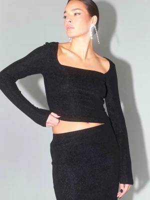Svart glittrig långärmad topp - Trendig svart topp med glittrigt tyg och fyrkantig ringning. Långärmad modell med tight passform och croppad längd. Perfekt för dig som vill sticka ut med en snygg och modern look.