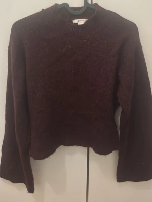 Vinröd stickad tröja Gina Tricot - Mysig vinröd stickad tröja från Gina Tricot med rund halsringning och långa ärmar. Tröjan har en enkel, klassisk design och är perfekt för att hålla värmen under kyliga dagar. Passar dig som gillar en basic men snygg look.
