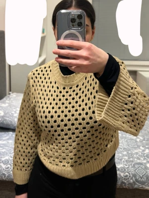 Beige stickad tröja med hålmönster - Trendig beige stickad tröja med grovt hålmönster och vida ärmar. Tröjan har ribbstickade muddar vid ärmslut och nederkant samt rund halsringning. Perfekt att styla lager på lager för en cool look.