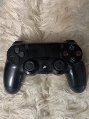  PlayStation 4 kontroll - Säljer en svart PlayStation 4 DualShock handkontroll med klassiska PlayStation-knappar och touchpad. Ergonomisk design i plast med analogspakar och styrkors. Perfekt för gaming på PS4.