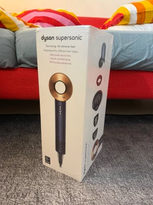 Dyson Supersonic hårfön koppar/svart - Säljer en Dyson Supersonic hårfön i snygg koppar och svart design. Den har flera stylingtillbehör och är känd för snabb torkning utan extrem värme. Perfekt för dig som vill ha kontrollerad styling och skydda hårets naturliga glans.