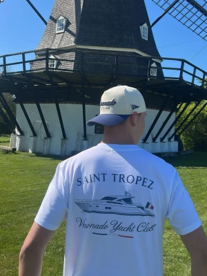 Voronado Saint Tropez t-shirt - Vit t-shirt från Voronado Yacht Club med stort tryck på ryggen som visar en yacht, texten 'SAINT TROPEZ' och franska flaggans färger. Klassisk passform och korta ärmar, perfekt för en avslappnad och stilren look.