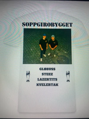 Vit Soppgirobygget t-shirt - Vit t-shirt med tryck av två personer på framsidan och texten 'SOPPGIROBYGGET' samt namn och ölglas. Rak passform och rund hals. Perfekt för dig som gillar streetwear och vill sticka ut med ett unikt motiv.