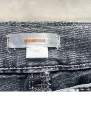 Grå jeans med broderade fickor Gina Tricot - Snygga grå jeans från Gina Tricot med unika broderade detaljer på bakfickorna och ficklock med knapp. Klassisk femficksmodell i mjukt denimtyg. Perfekta för dig som vill sticka ut med coola detaljer.